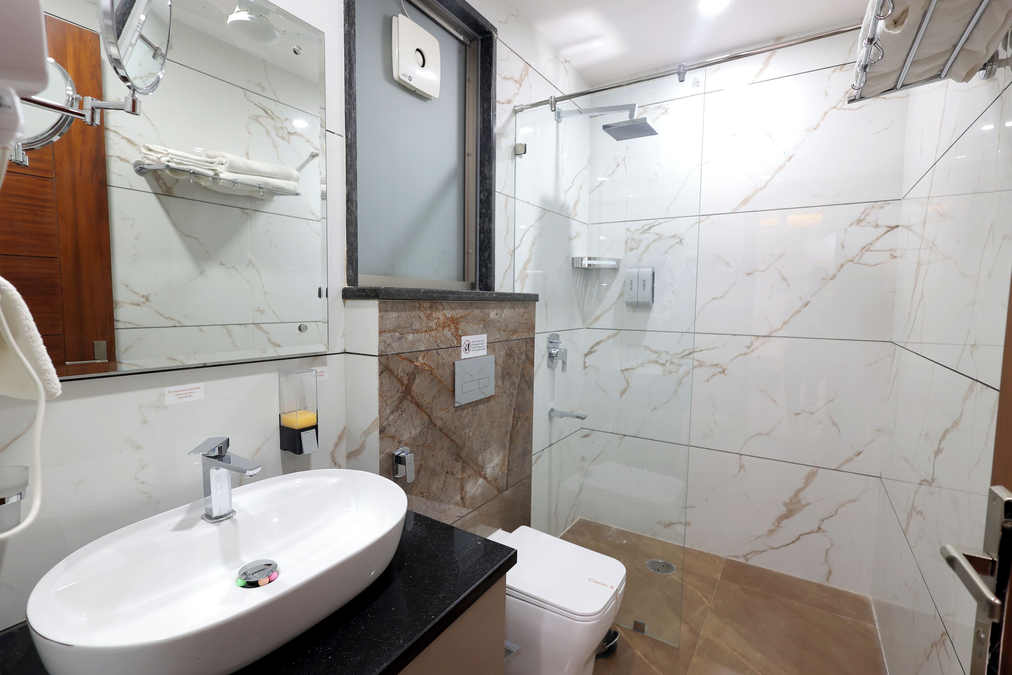 A modern bathroom with a white sink, mirror, and glass shower enclosure.