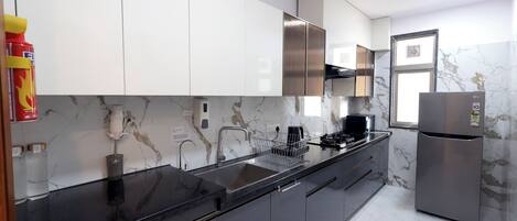 Cocina moderna con armarios blancos, refrigerador de acero inoxidable y salpicadero de mármol.