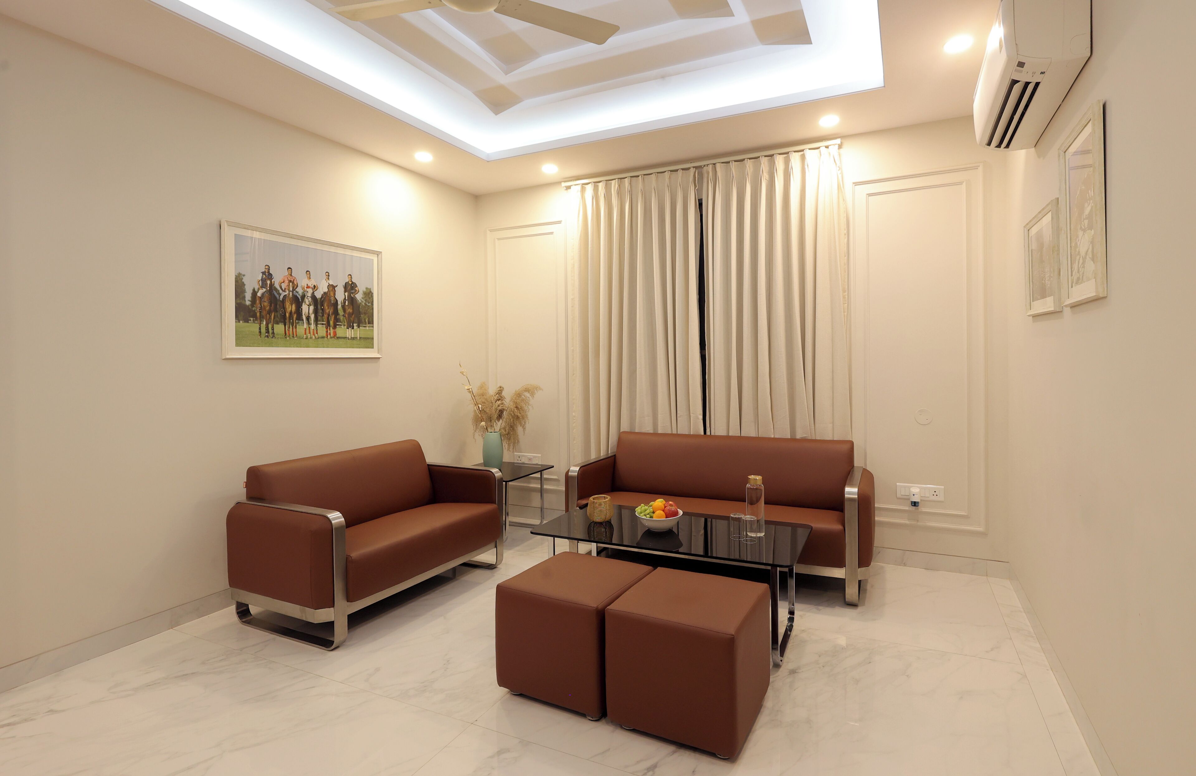Uma sala de estar moderna com dois sofás marrons, uma mesa de centro de vidro e uma mesa lateral com um vaso e uma fruteira.