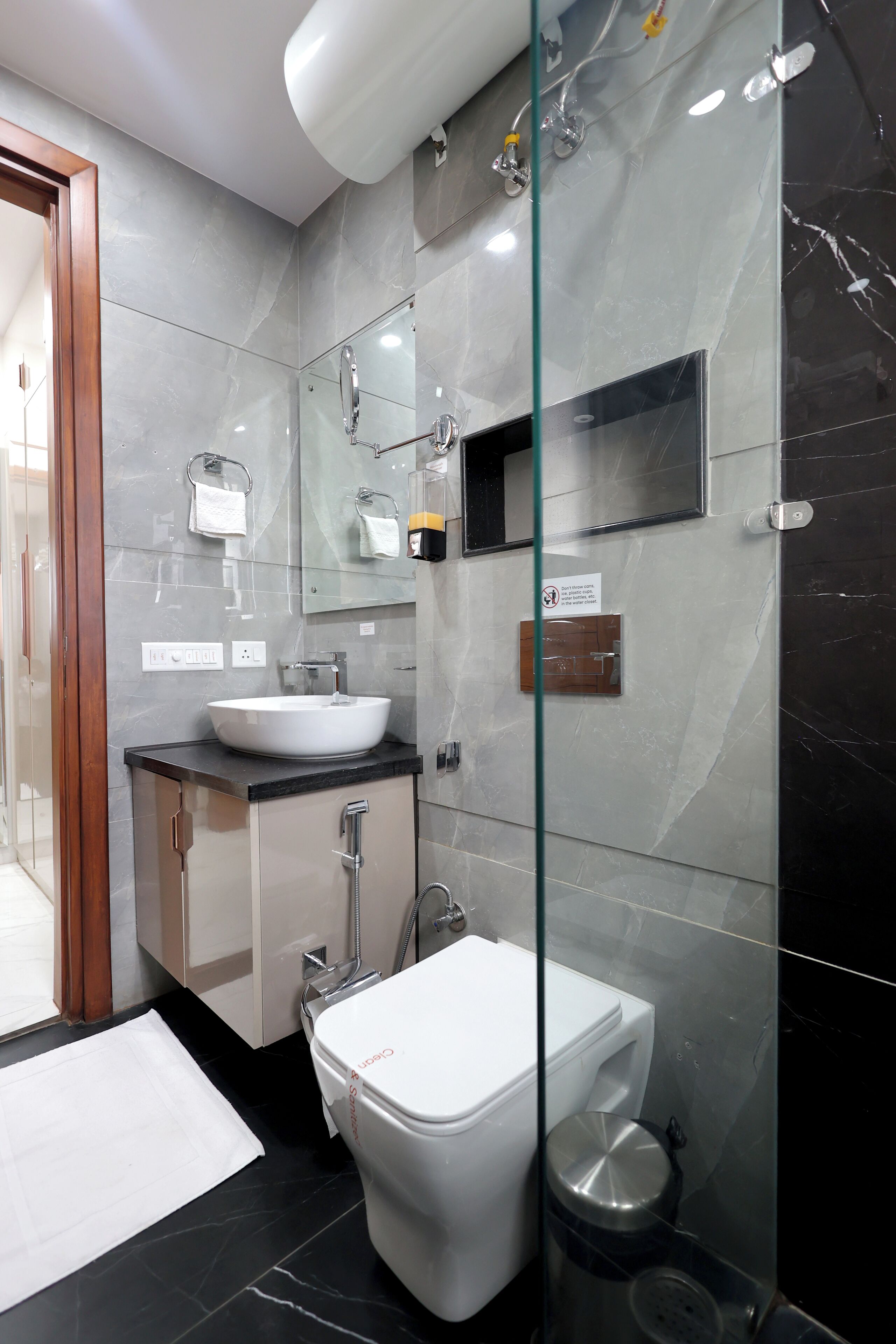 Un baño moderno con cabina de ducha de vidrio, un lavabo blanco y un inodoro.