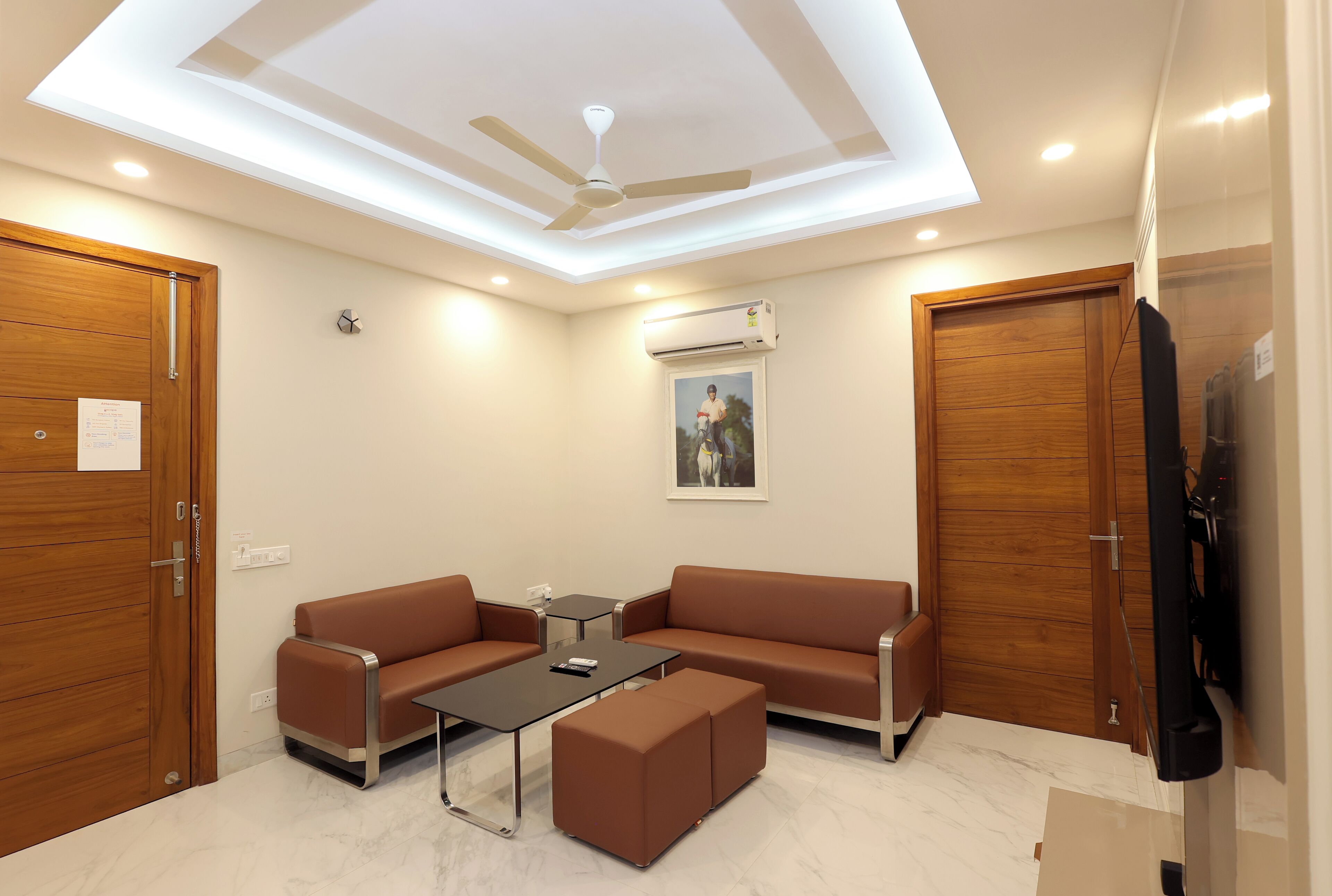 A modern waiting area with a ceiling fan, a sofa, a coffee table, and a TV.