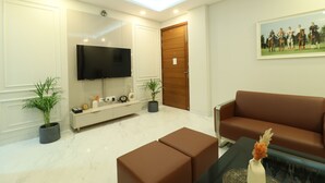 Una sala de estar moderna con televisor de pantalla plana, un sofá marrón, una mesa de centro y una planta en maceta.