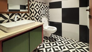 A bathroom with a geometric patterned floor, a sink with a mirror above it, and a toilet.