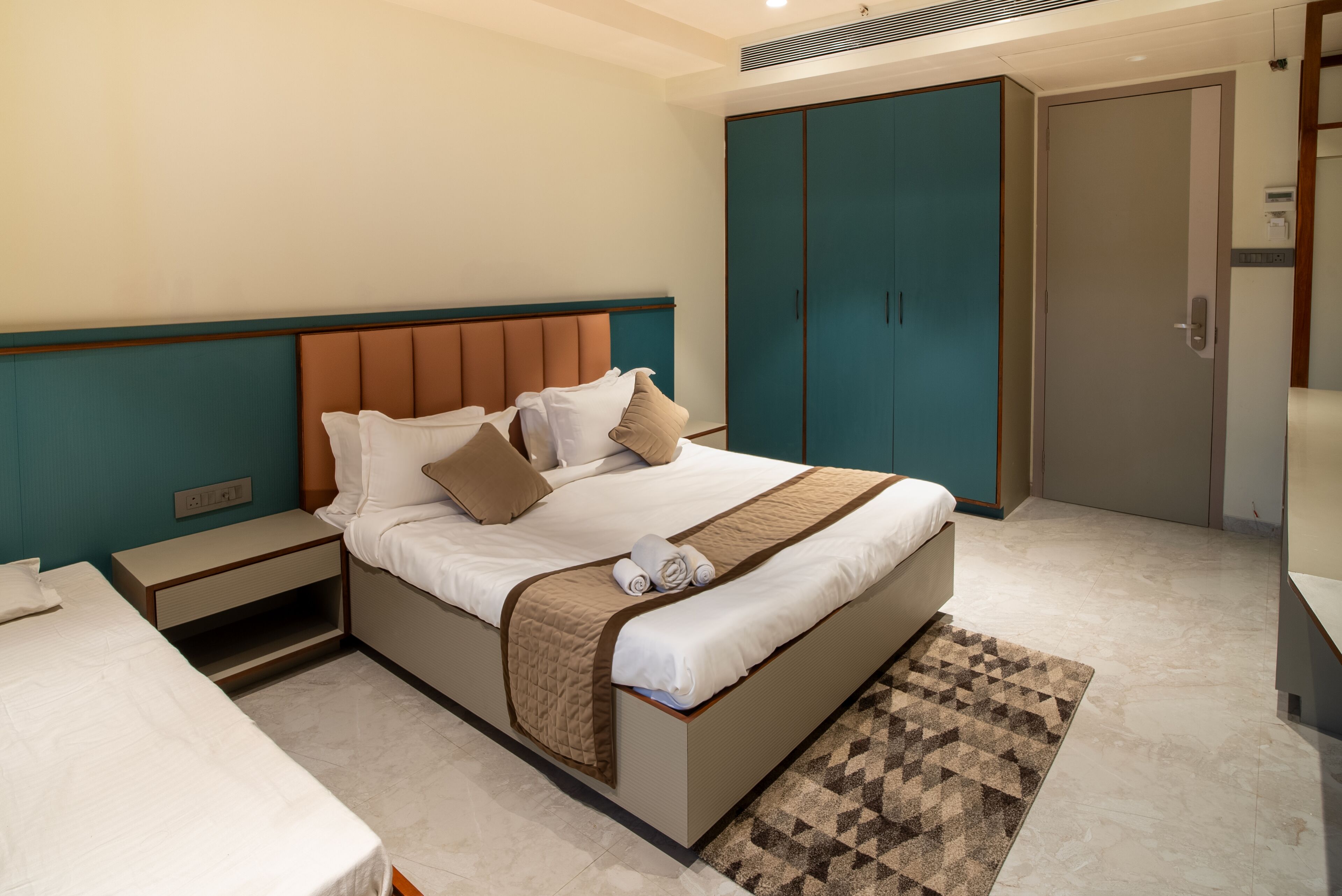 Une chambre d’hôtel moderne avec un grand lit, une table de chevet, une armoire et une porte de salle de bain.