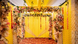 A decorated indoor space with a patterned carpet, yellow walls, and floral arrangements.