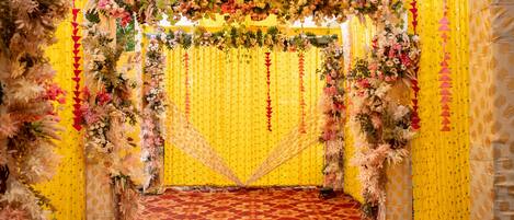 Un espacio interior decorado con alfombra estampada, paredes amarillas y arreglos florales.