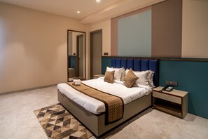 Habitación de hotel moderna con una cama grande, una mesita de noche con teléfono y un espejo.