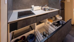 A modern kitchen with a built-in stove, sink, and storage drawers. - Hida machiyado KESHI (Takayama)