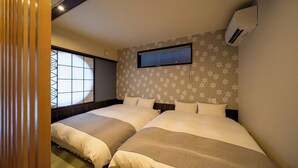A hotel room with two beds, a window with a geometric pattern, a wall-mounted air conditioner, and a star-patterned wall. - Hida machiyado KESHI (Takayama)