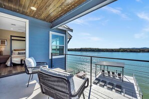 Ein Balkon mit Blick auf einen See, möbliert mit Stühlen und einem Tisch.