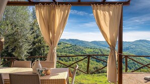 Ein überdachter Außenbereich mit Tisch für zwei Personen, mit Blick auf eine Berglandschaft.