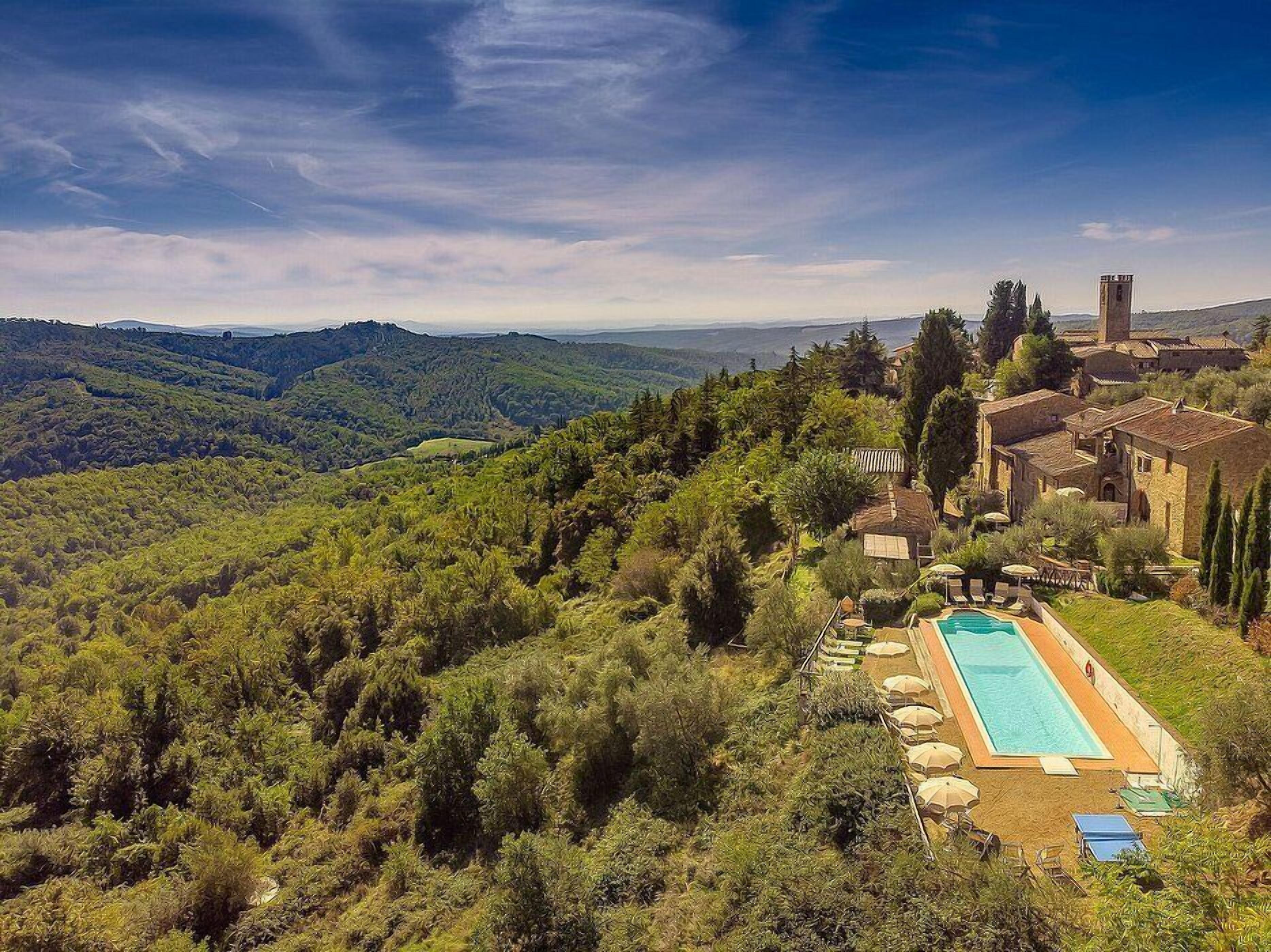 A villa with a swimming pool, surrounded by lush greenery and hills.