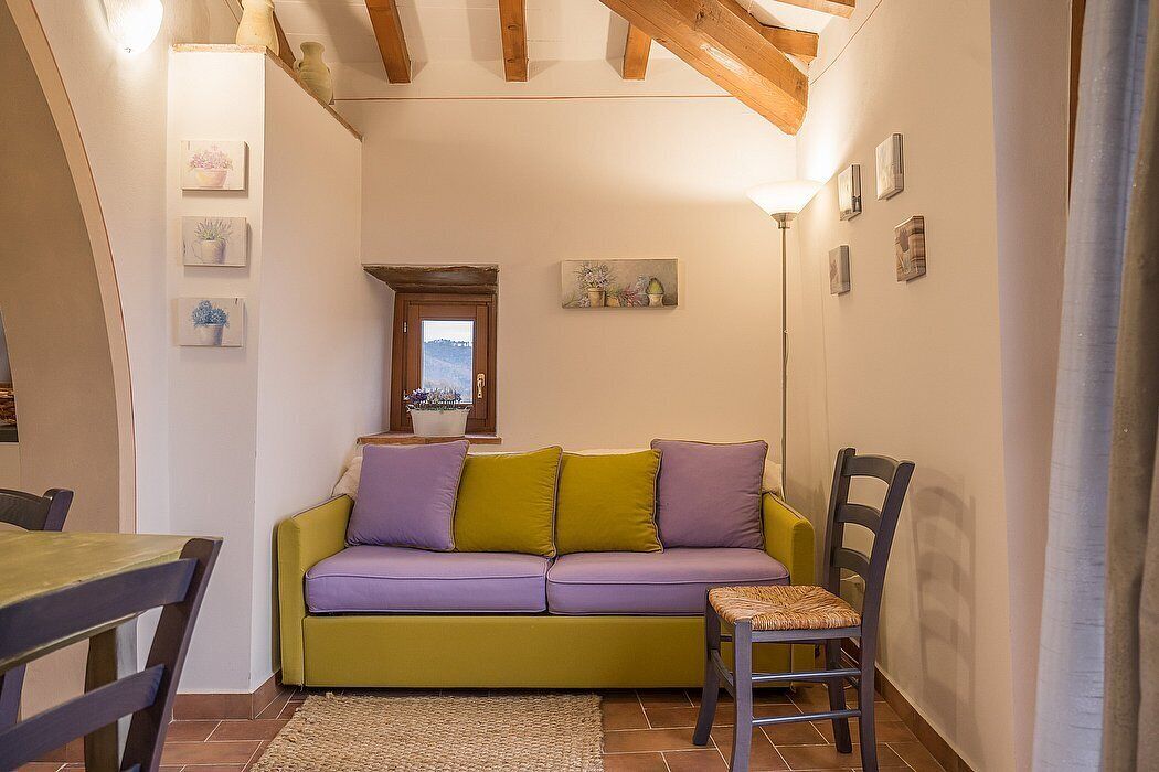 Un salon confortable avec un canapé, une table à manger et des chaises. Une fenêtre offre une vue sur le paysage.