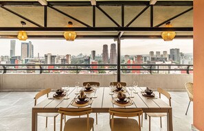 Enjoy a meal with a city view from this dining area featuring a high ceiling and exposed beams.