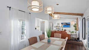 A dining area with a large table, chairs, and hanging wicker light fixtures. - Stunning, Cozy, Private Backyard Lush Oasis with Pool! BBQ, 14 Mins to Disney (Santa Ana)