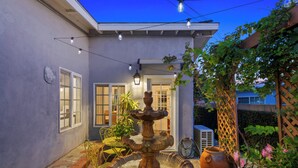 A courtyard with a central fountain, outdoor seating, and a pergola with climbing plants. - Stunning, Cozy, Private Backyard Lush Oasis with Pool! BBQ, 14 Mins to Disney (Santa Ana)