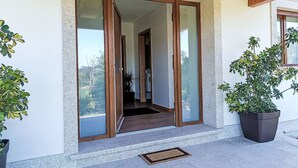 Ein moderner Eingangsbereich mit Glastüren, einem Betonweg und Kübelpflanzen.