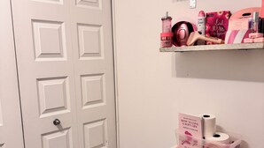 Een badkamer met een toilet, een plank met toiletartikelen en een deur.