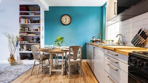A modern kitchen with a teal accent wall, wooden flooring, and a dining area with a wooden table and chairs.
