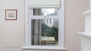 A room with a white window, a framed picture on the wall, and a white chair. - Traditional Bath House, Garden with City Views (Bath and North East Somerset)