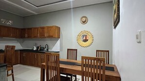 Un comedor con mesa y sillas de madera, una cocina al fondo y un espejo decorativo en la pared.