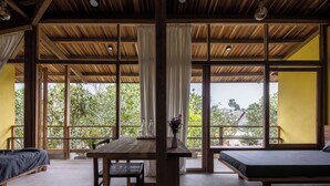 A room with a wooden ceiling, large windows, a table with chairs, and two beds. - Hachi Homestay & Spa (Hue)