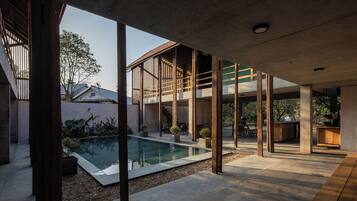 A modern outdoor space with a swimming pool, wooden deck, and a covered seating area.