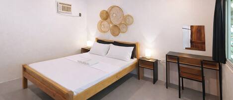 A bedroom with a wooden bed, bedside tables, a desk, and a wall-mounted decorative item.