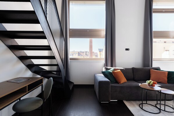 Relax in a spacious living area with a sofa, table, and chair, offering a view of the city.
