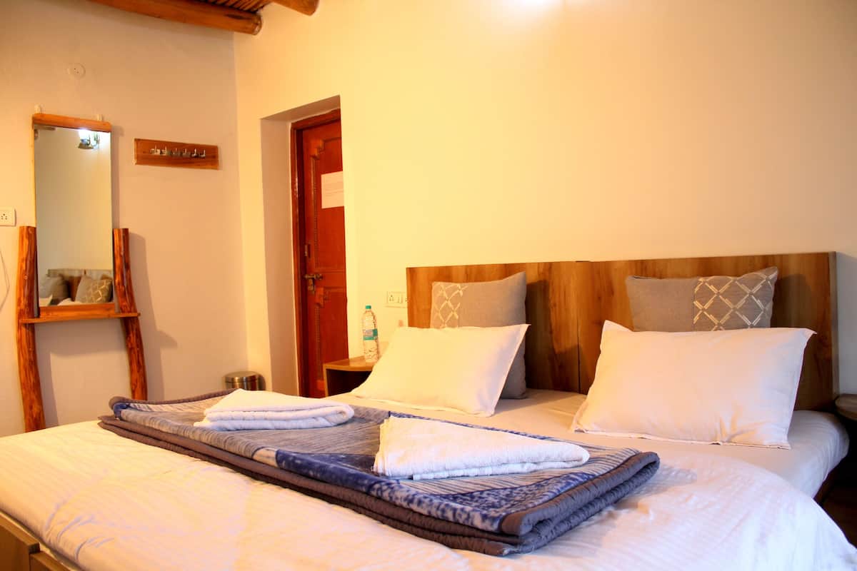 Una cama bien hecha con una colcha azul y blanca, un cabecero de madera y dos almohadas.