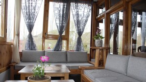 A cozy living room with a grey sofa, a wooden coffee table with a decorative bowl, and a potted plant. - Karma Lodge (Leh)