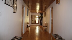 A hallway with wooden flooring, a bench, and framed pictures on the walls. - Karma Lodge (Leh)