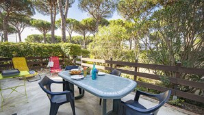 An outdoor patio with a table and chairs, surrounded by a wooden fence and trees.