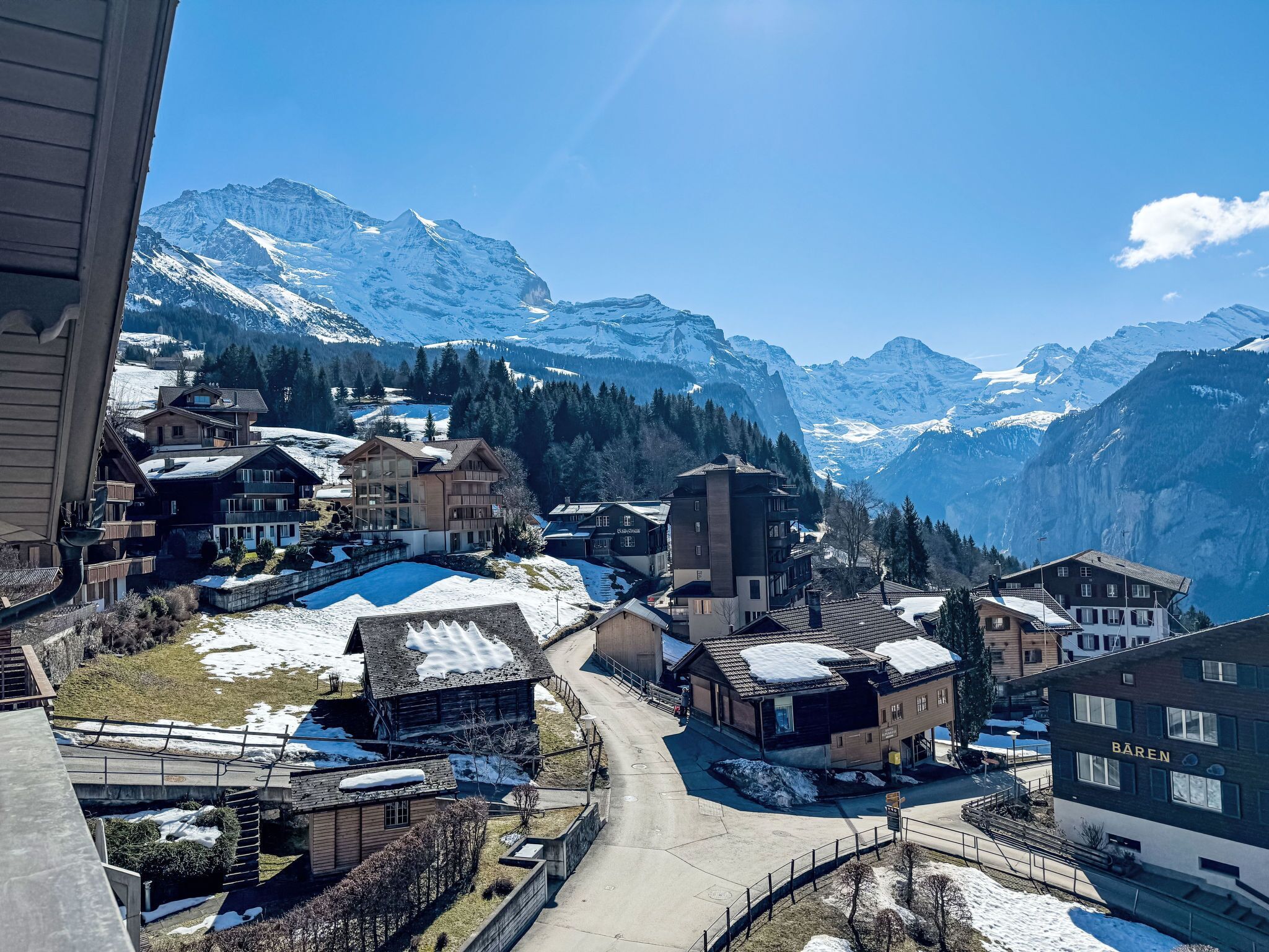 Ein Bergdorf mit schneebedeckten Häusern und freiem Blick auf die umliegenden Berggipfel.