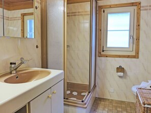 Bathroom features a large mirror, sink, and shower with a glass door.