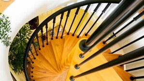 Un escalier en colimaçon avec des marches en bois et des rampes en métal noir.