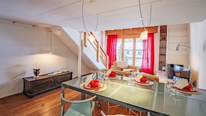 Un comedor con mesa de vidrio, sillas de metal y piso de madera.