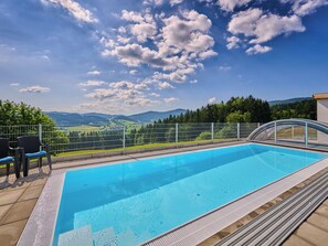 Ein Schwimmbad mit Blick auf Berge und einem Zaun.