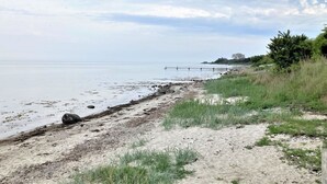 A beach with a sandy shore, a pier extending into the water, and some greenery in the background. - "Bjart" - 150m from the sea by Interhome (Hesselager)