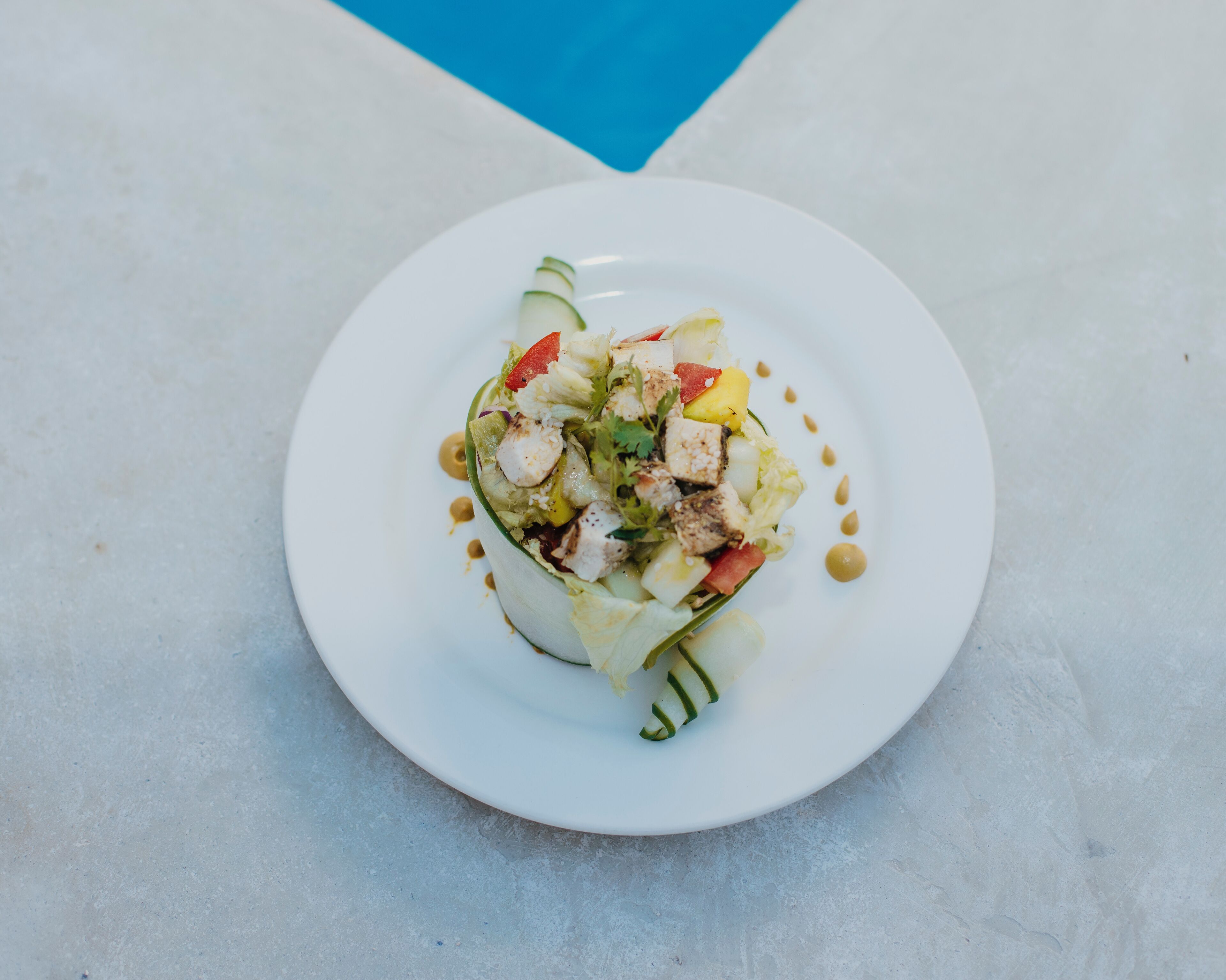A white plate with a salad on a marble surface.