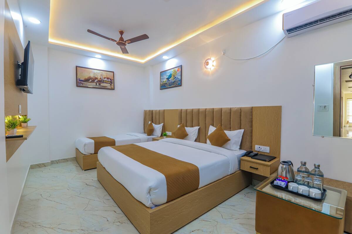 A hotel room with a large bed, a bedside table, a mirror, and a ceiling fan.