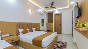 Une chambre d’hôtel moderne avec un grand lit, des tables de chevet, un ventilateur de plafond, un appareil de climatisation, une télévision et une petite plante.