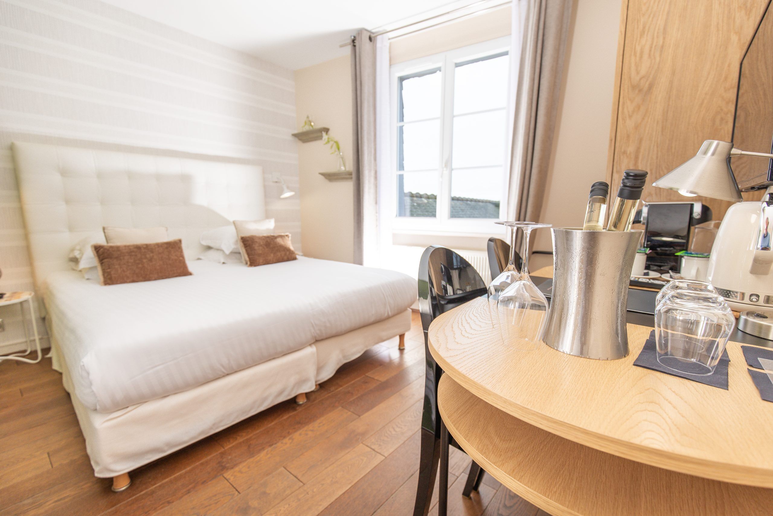 Habitación de hotel con cama, una mesa de madera, cafetera y ventana con cortinas.