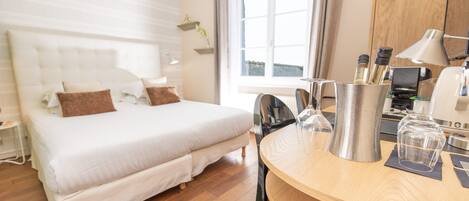 Habitación de hotel con cama, una mesa de madera, cafetera y ventana con cortinas.