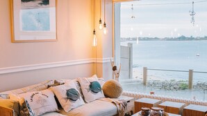 A cozy living room with a sofa, coffee table, and a view of the sea. - Hôtel la Baie des Anges, son SPA marin et sa piscine couverte et chauffée (Landéda)