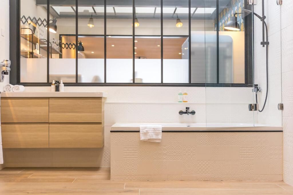 Ein modernes Badezimmer mit einem Holzbadezimmer-Möbelkorpus, einem großen Spiegel und einer Badewanne.