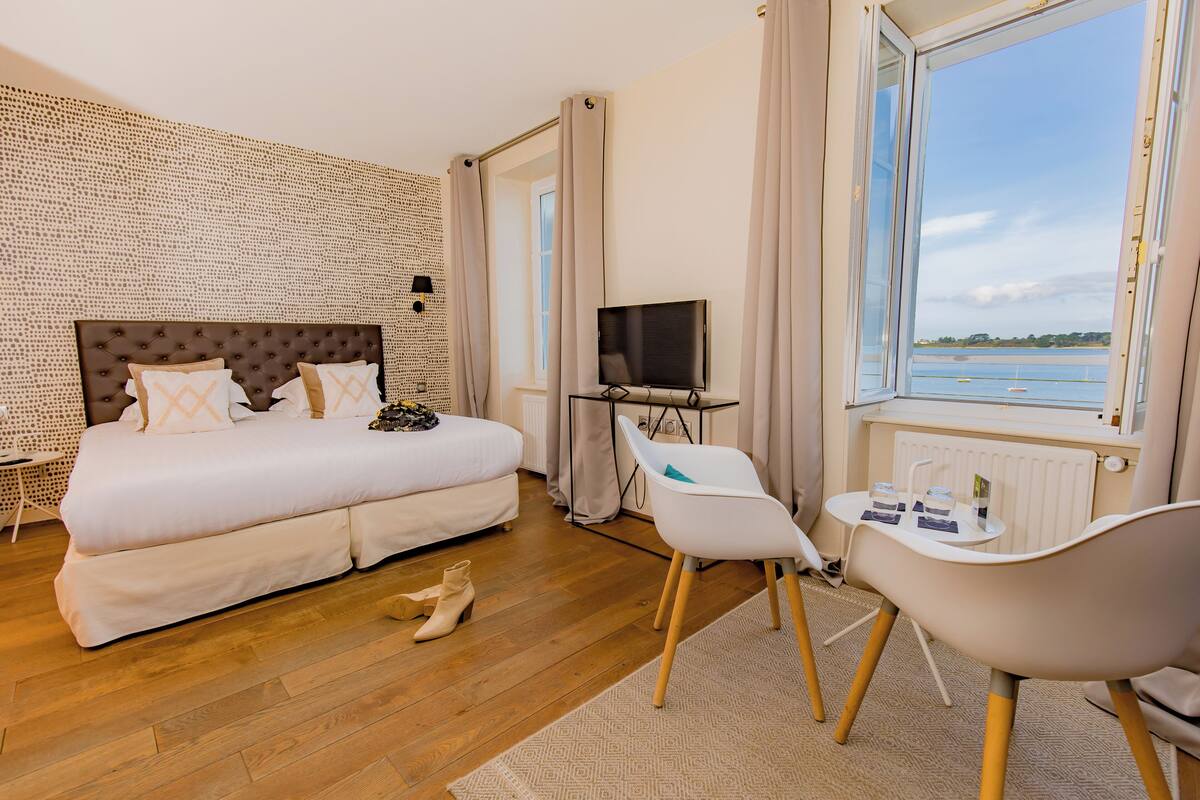 A bedroom with a large bed, a TV, a small table, and a chair.