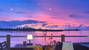 A seaside restaurant with outdoor seating, a view of the water, and a sunset. - Hôtel la Baie des Anges, son SPA marin et sa piscine couverte et chauffée (Landéda)