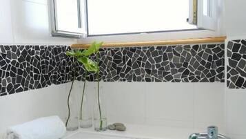 Un baño moderno con bañera, ventana y un salpicadero de mosaicos.