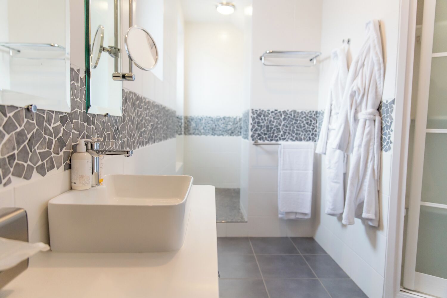 Un baño moderno con un lavamanos grande rectangular, una cabina de ducha con mampara de vidrio y un salpicadero de azulejos.